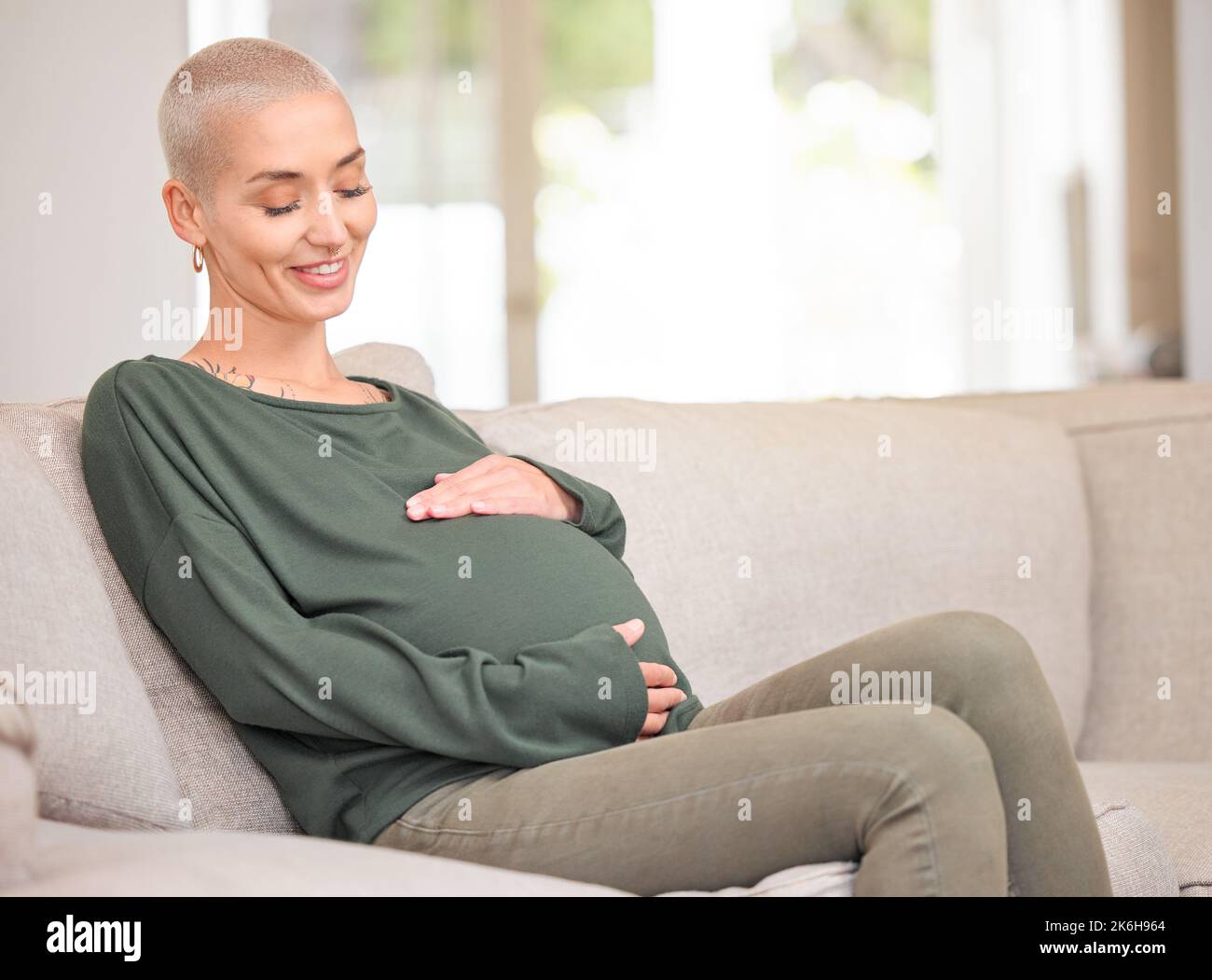 I cant wait to meet you. an attractive young pregnant woman rubbing her belly while sitting on the sofa at home. Stock Photo