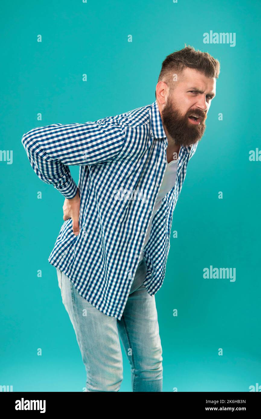 Bent over feeling sharp pain in back. Bearded man suffer from pain