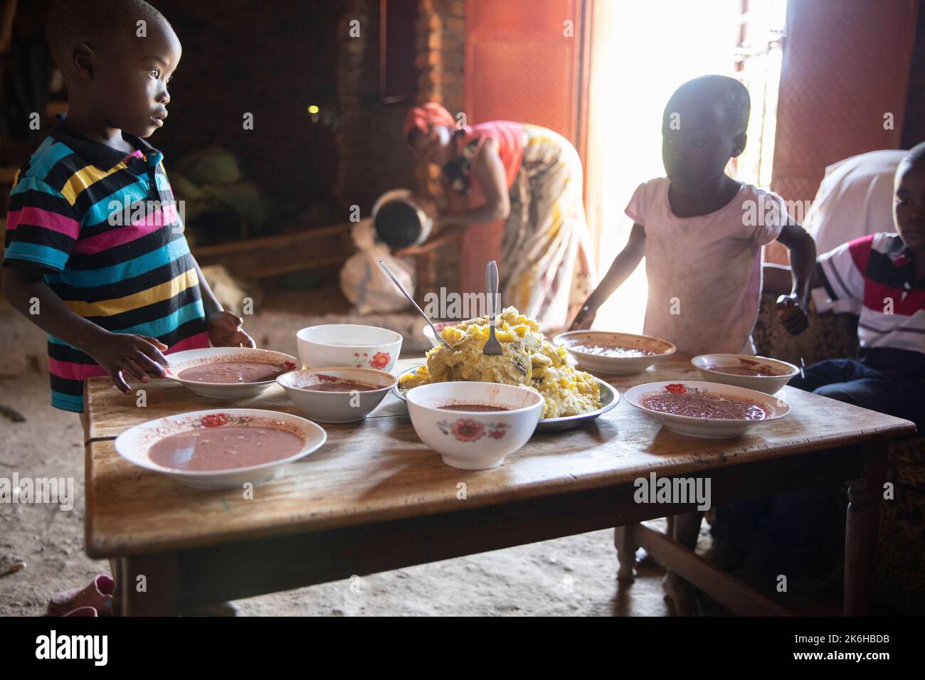 Ugandan family sharing a meal of beans and mashed savory bananas together in their home in Kasese District, Uganda, East Africa. Stock Photo