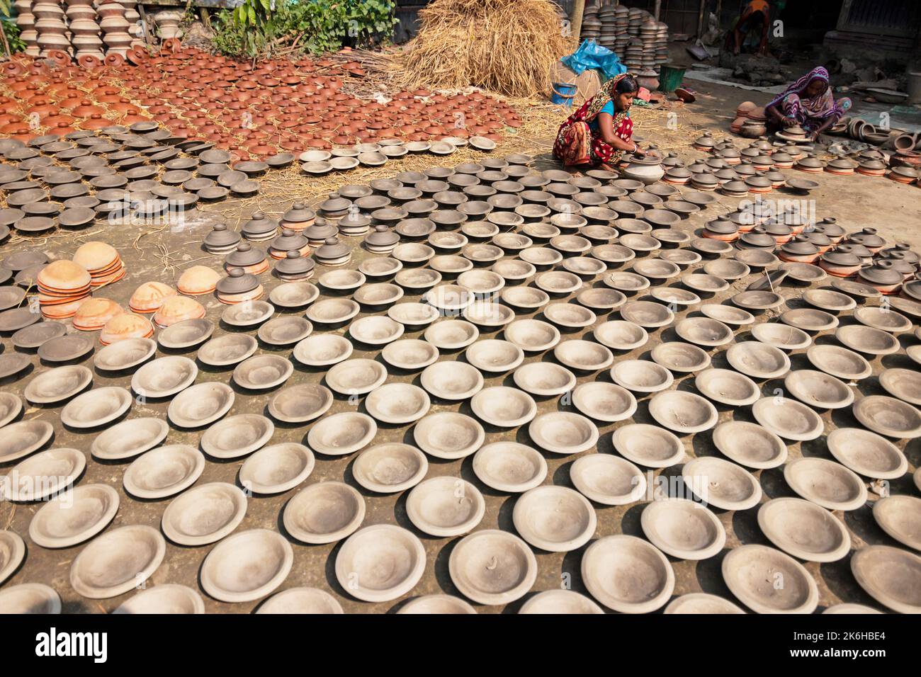Workers make clay pots as a form of pottery business to sell at a market. The clay pots are laid