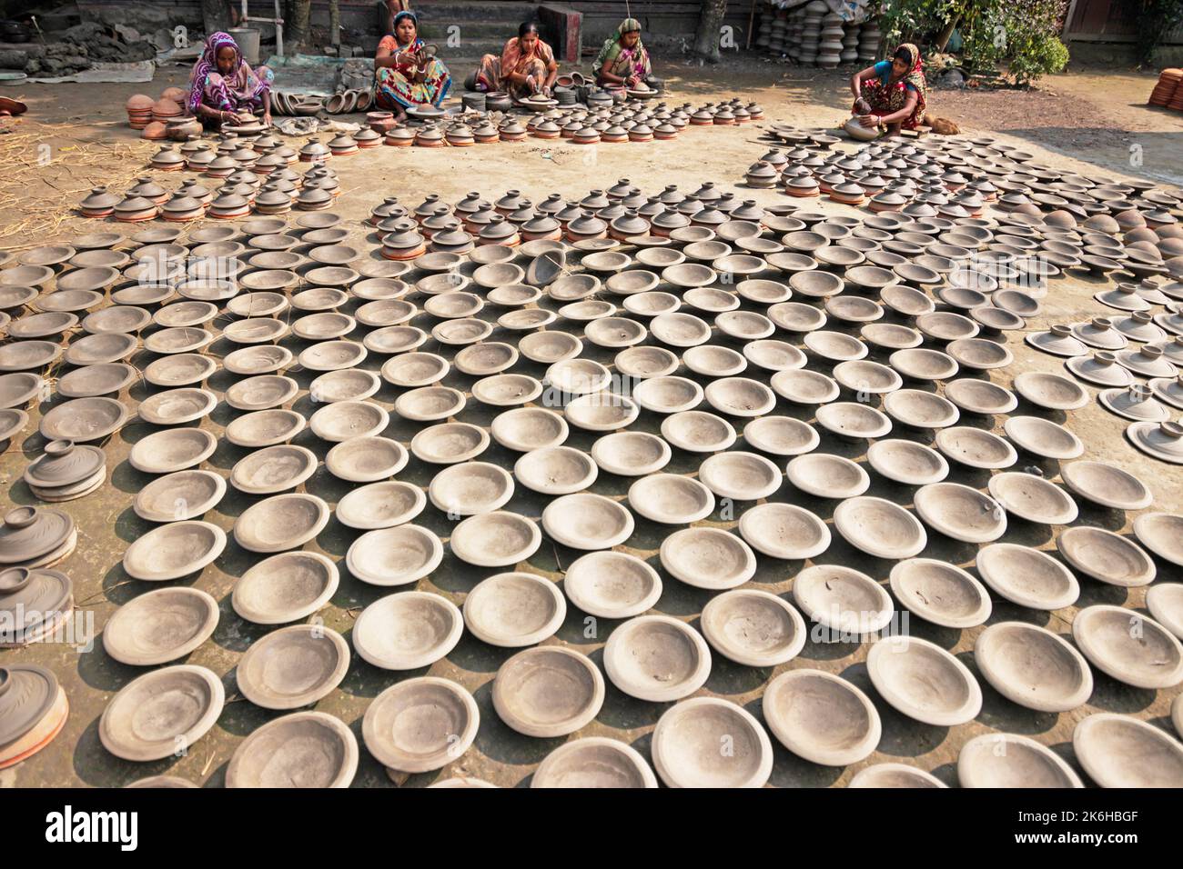 Workers make clay pots as a form of pottery business to sell at a market. The clay pots are laid