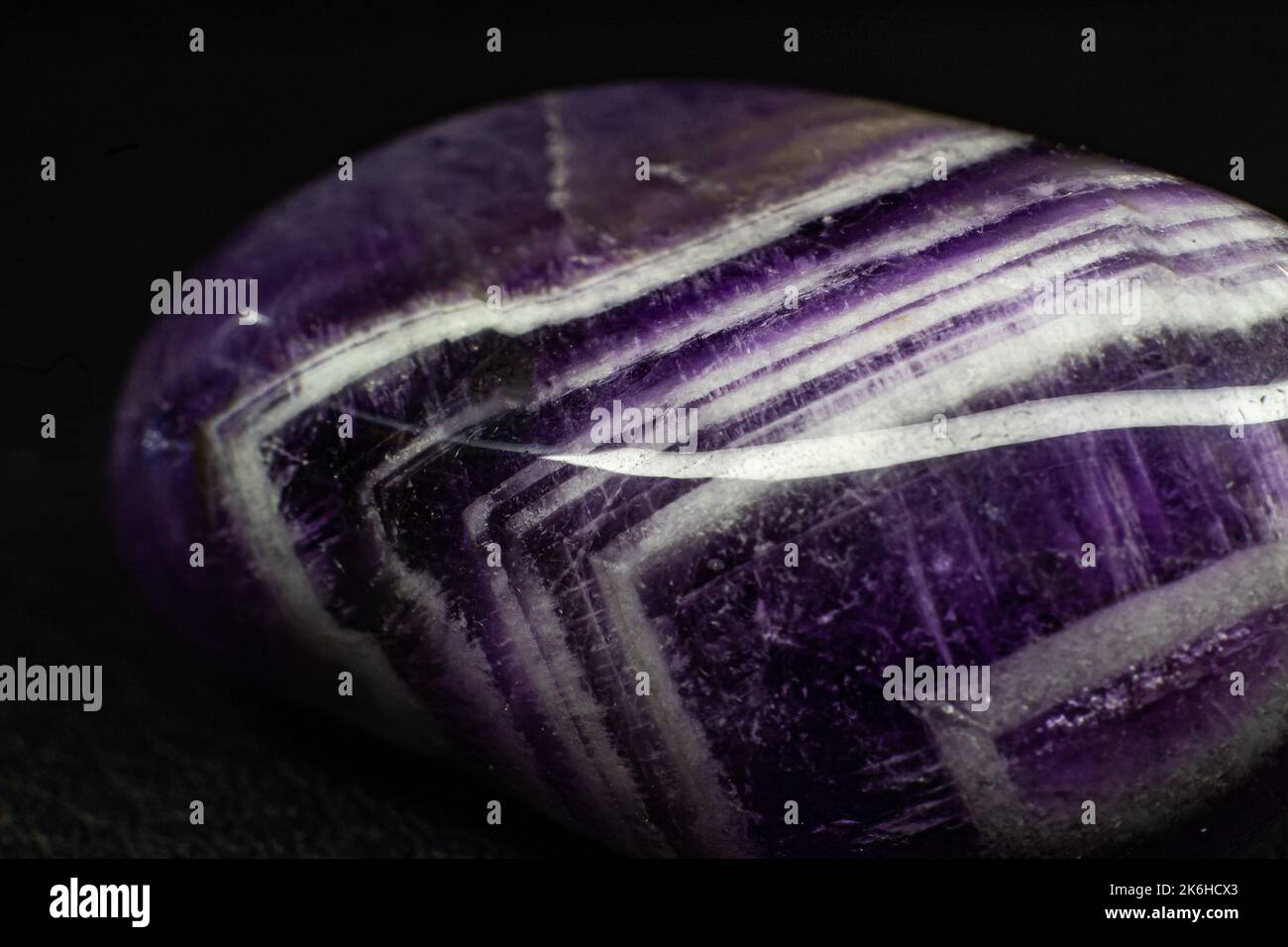 Real tumbled purple and white chevron amethyst focused on black surface macro Stock Photo