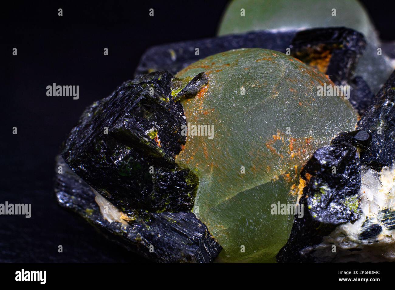 Chunk of real green prehnite spheres and dark green almost black epidote spikes on matrix macro isolated on black surface Stock Photo