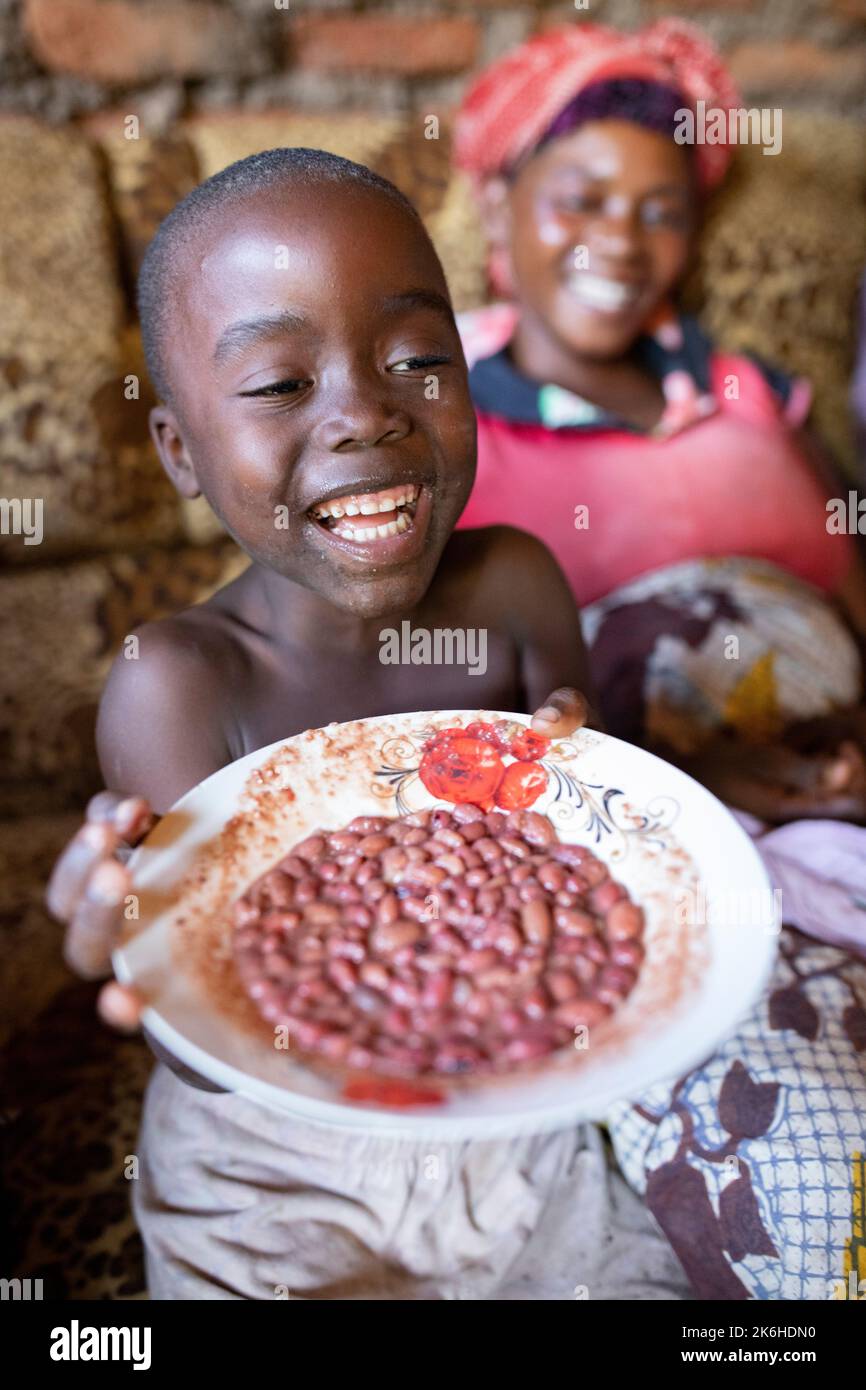 Ugandan family sharing a meal of beans together in their home in Kasese District, Uganda, East Africa. Stock Photo