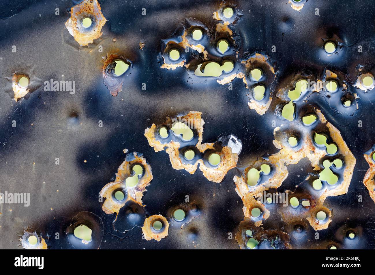 background of rusty bullet holes in a metal sign with textured peeling
