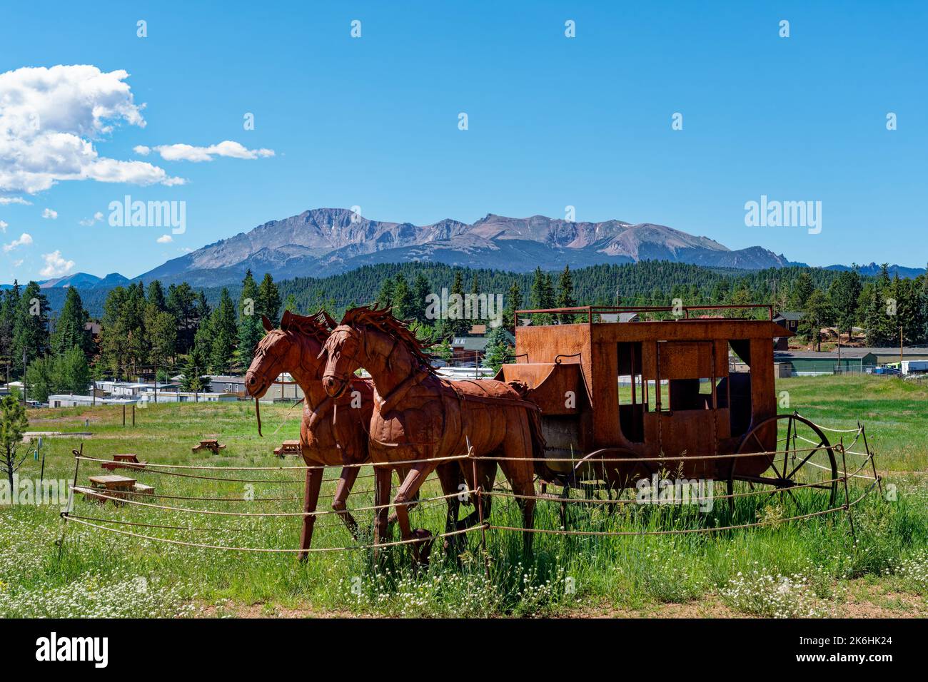 Woodland Park, CO - July 9, 2022: Rusty Metal horse and wagon sculpture behind the Colorado Midland Railway Depot and rest stop in Bergstrom Park with Stock Photo