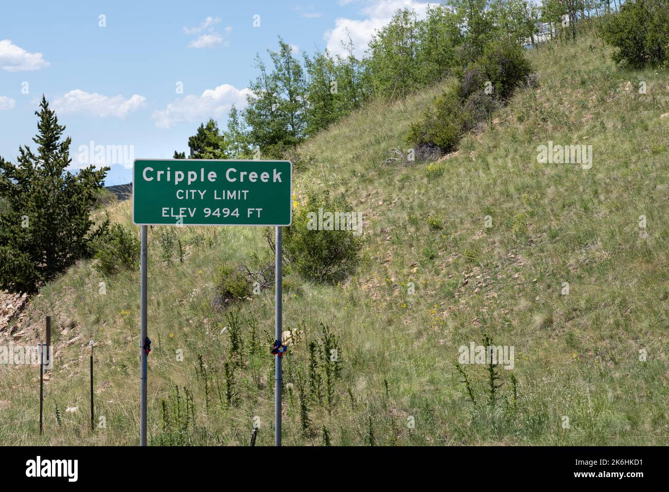 Cripple Creek, Colorado City Limit Elevation 9494 sign with grass covered hill behind Stock