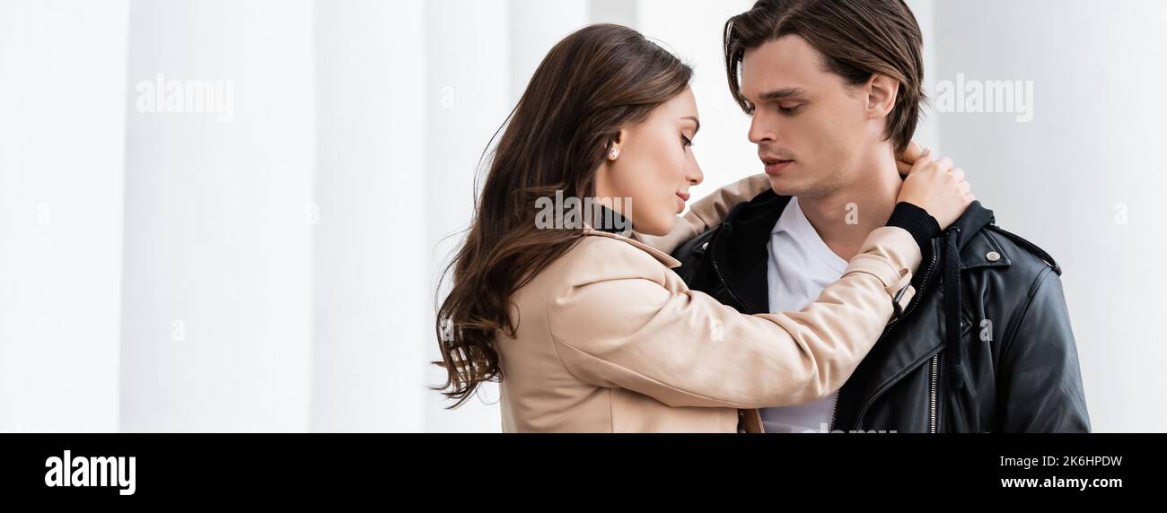 pretty young woman hugging boyfriend in black stylish jacket outdoors ...