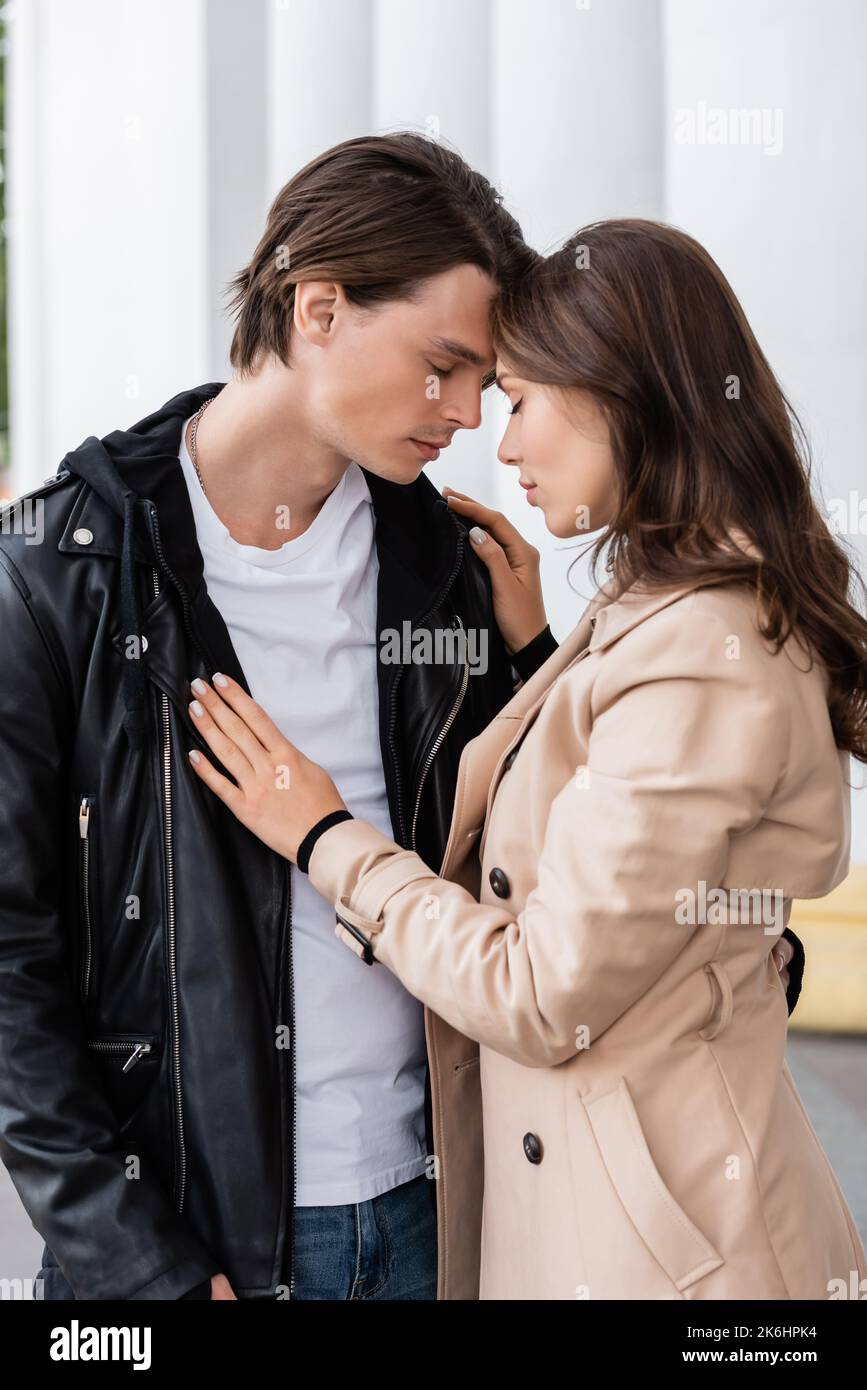 young woman in beige trench coat hugging boyfriend in stylish jacket ...