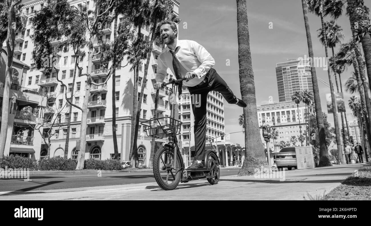 Happy employer in formalwear have fun riding escooter on sidewalk, recreation Stock Photo