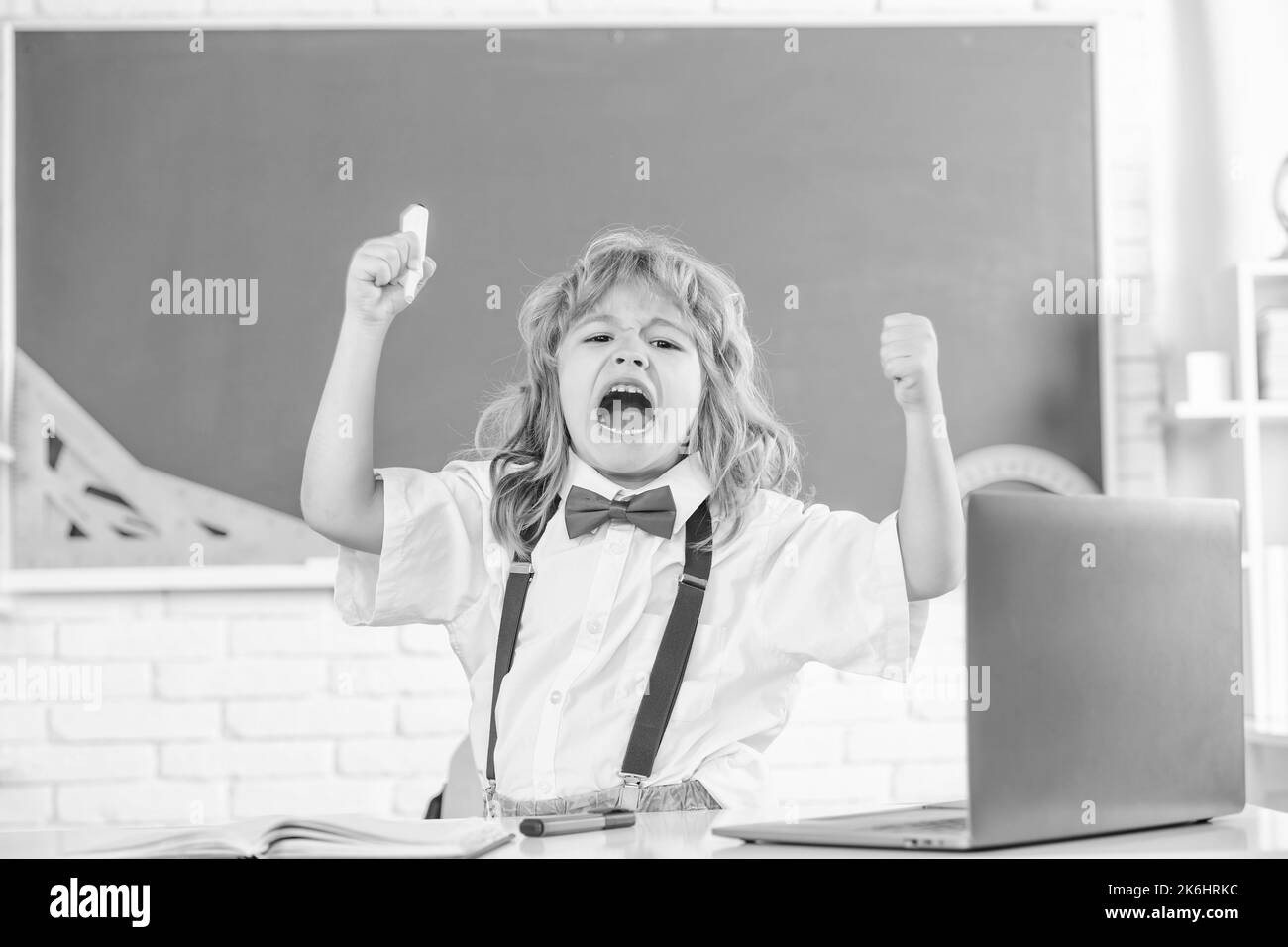 shouting kid boy in bow tie study in school classrrom at blackboard, emotions Stock Photo