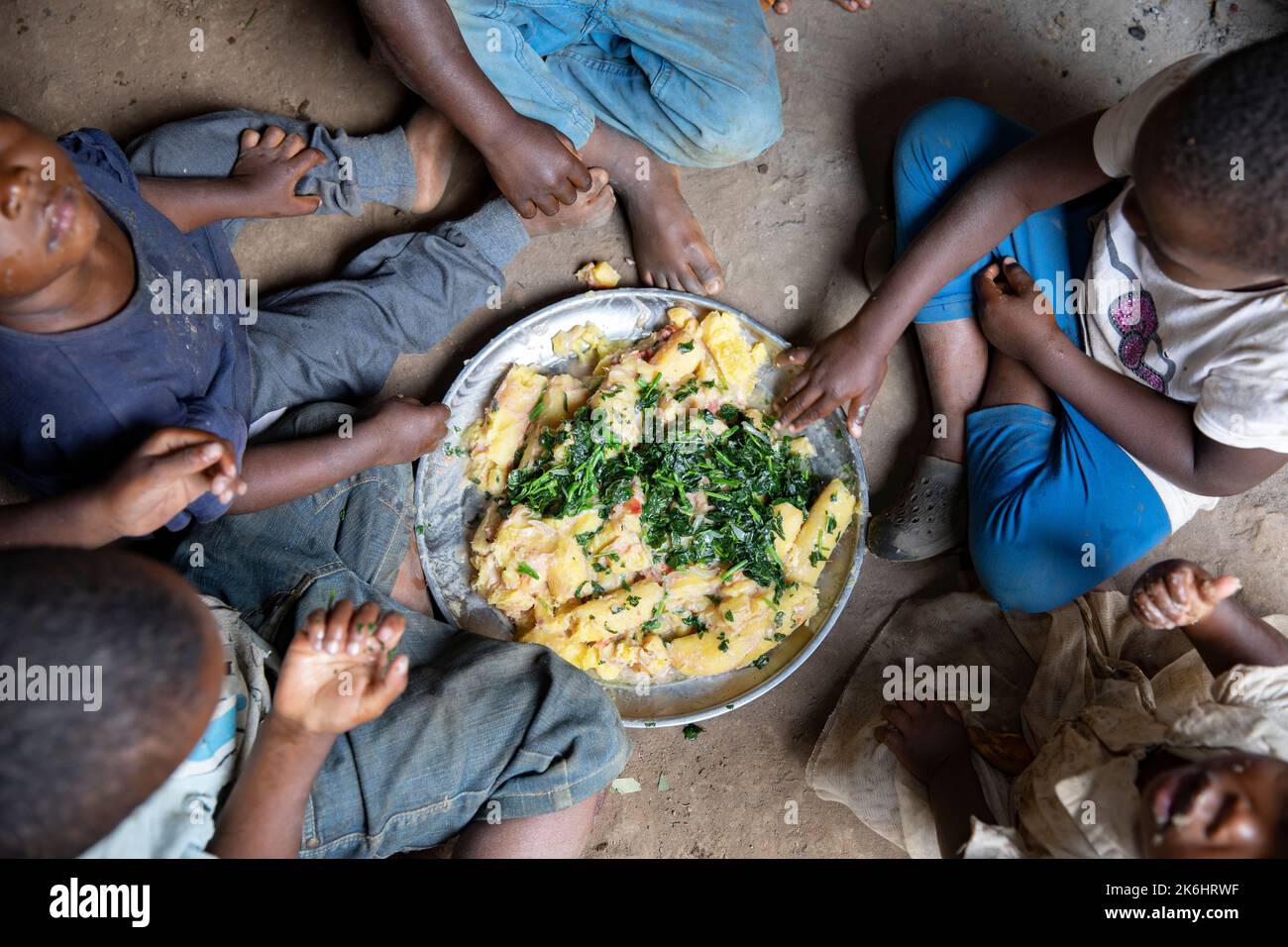 A group of African children eat a meal of starchy bananas and greens