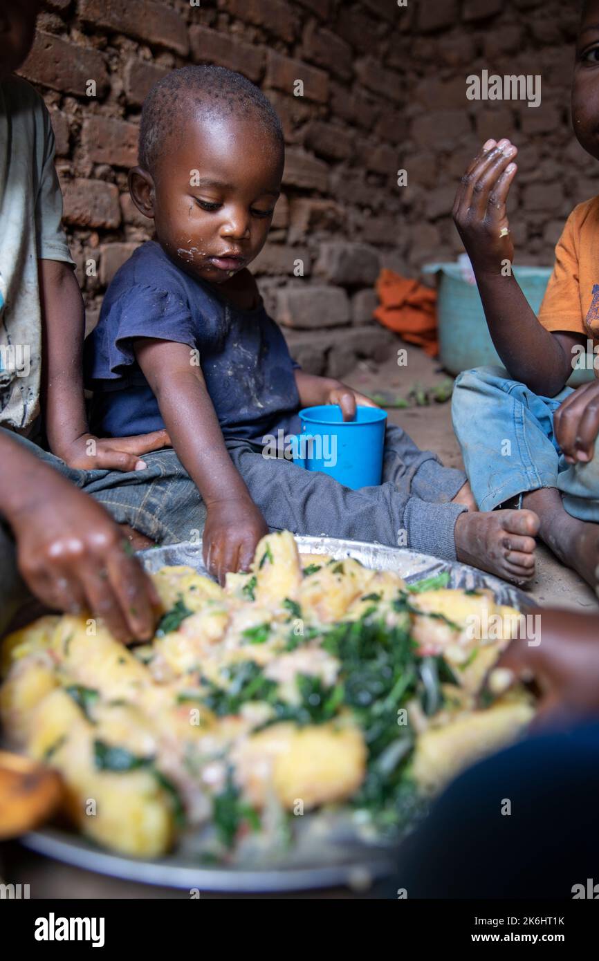 A group of African children eat a meal of starchy bananas and greens