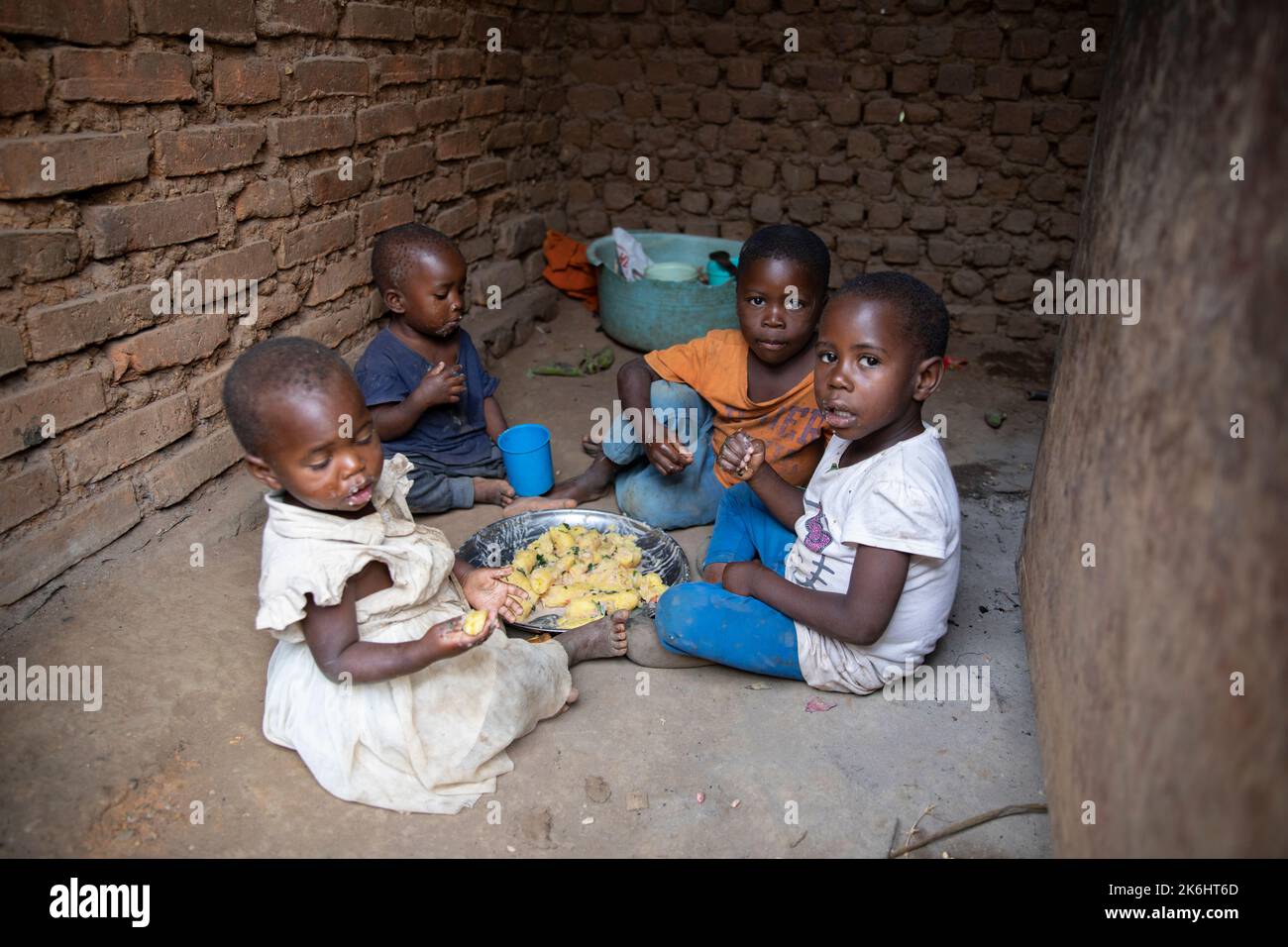 A group of African children eat a meal of starchy bananas and greens ...