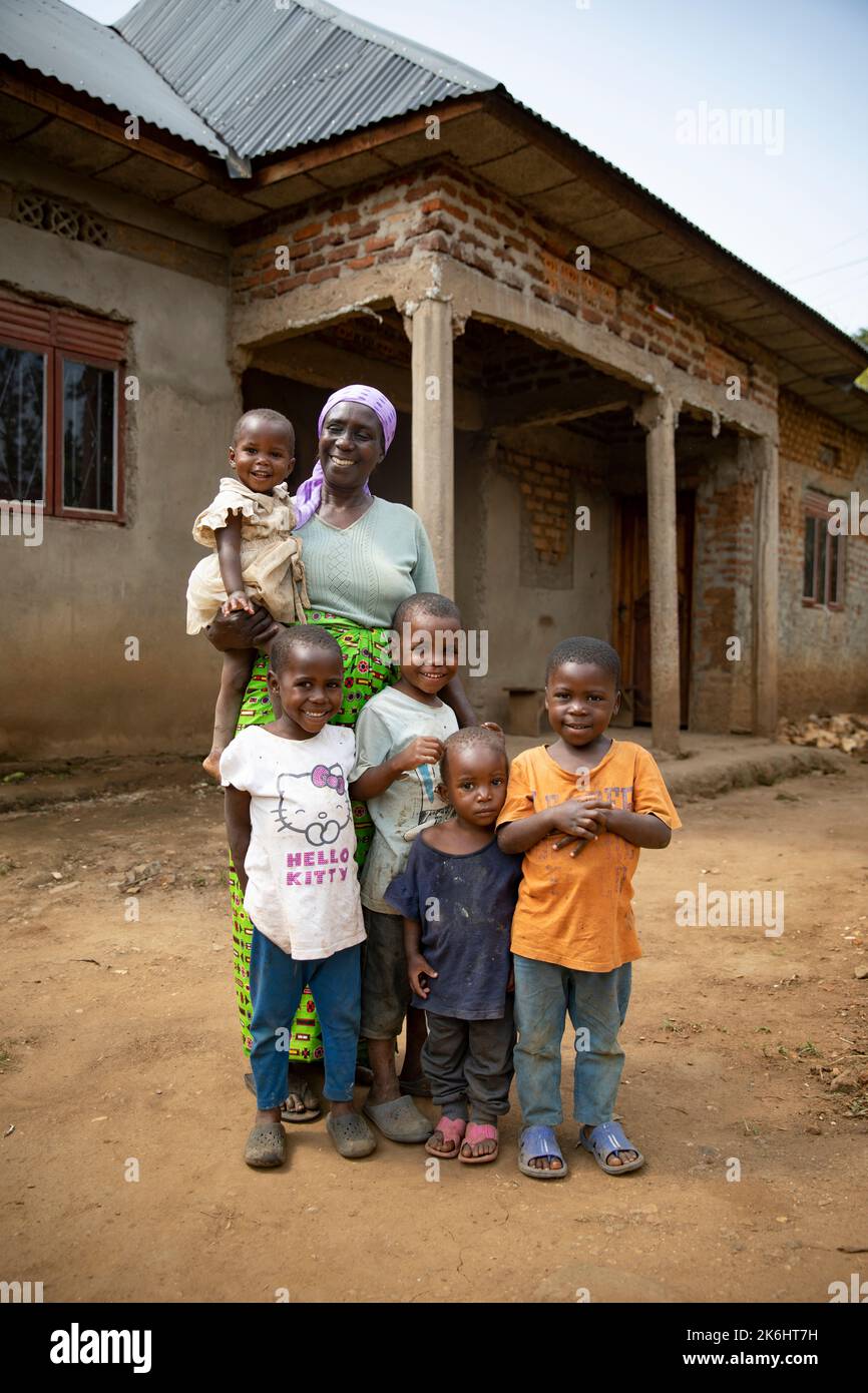 An elderly woman stands with her five grandchildren outside their brick home in Kasese District, Uganda, East Africa. Stock Photo