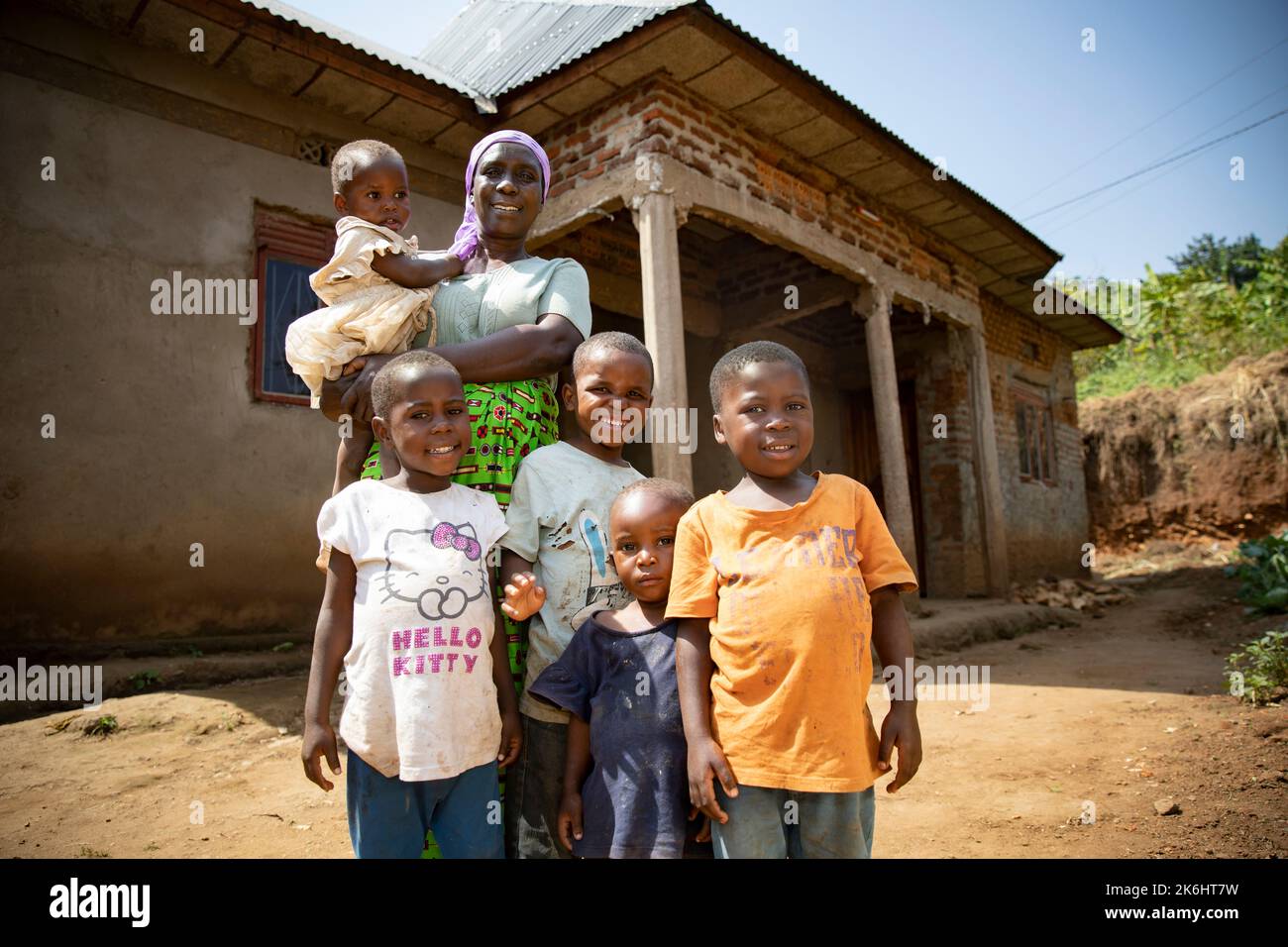 An elderly woman stands with her five grandchildren outside their brick home in Kasese District, Uganda, East Africa. Stock Photo