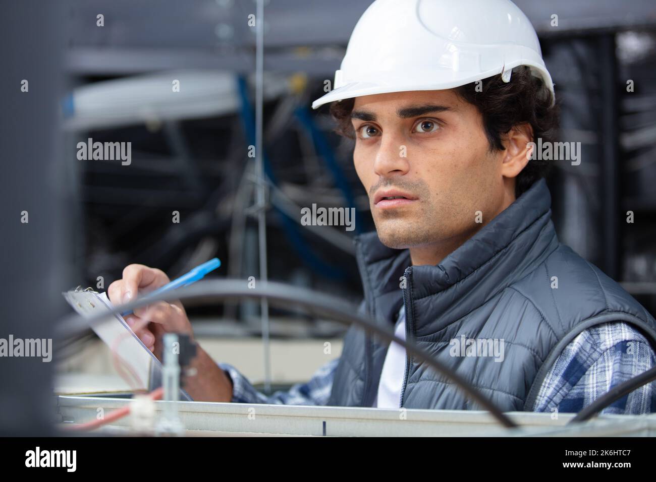 handsome young male builder writing on clipboard Stock Photo