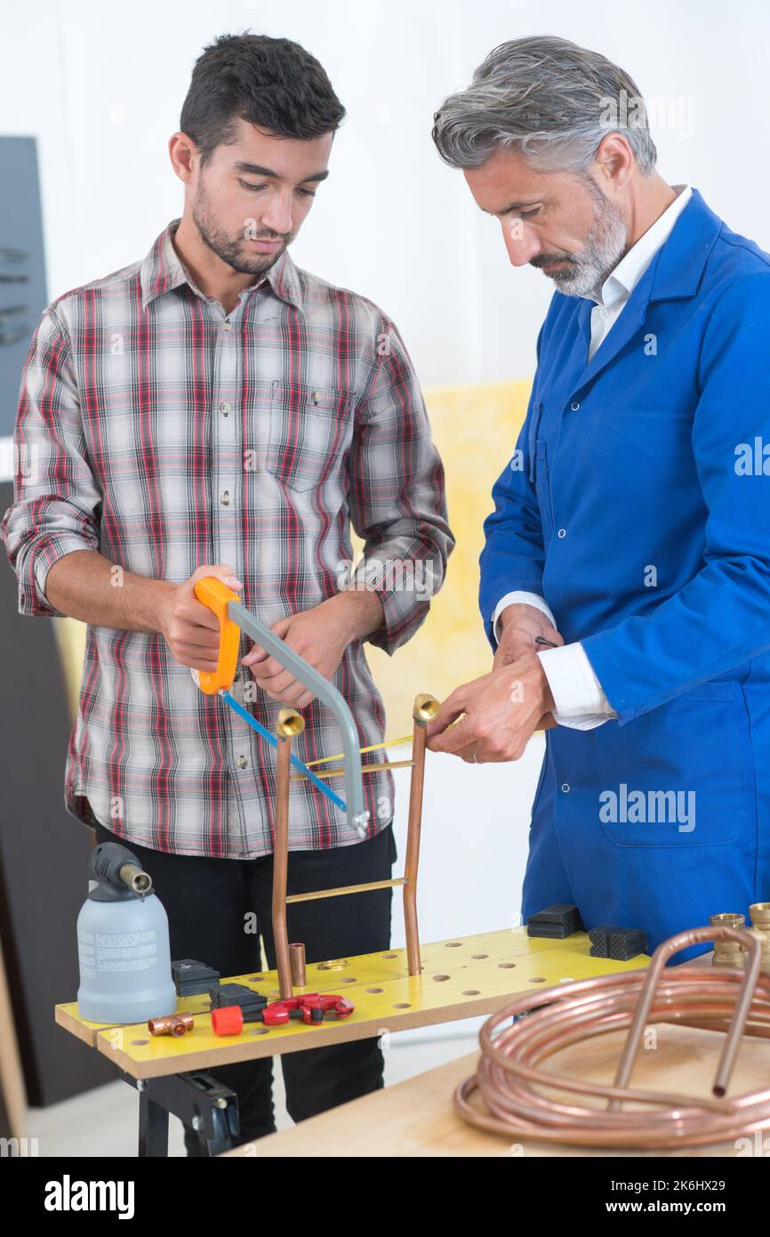 plumber using a hacksaw to cut down some pipes Stock Photo Alamy