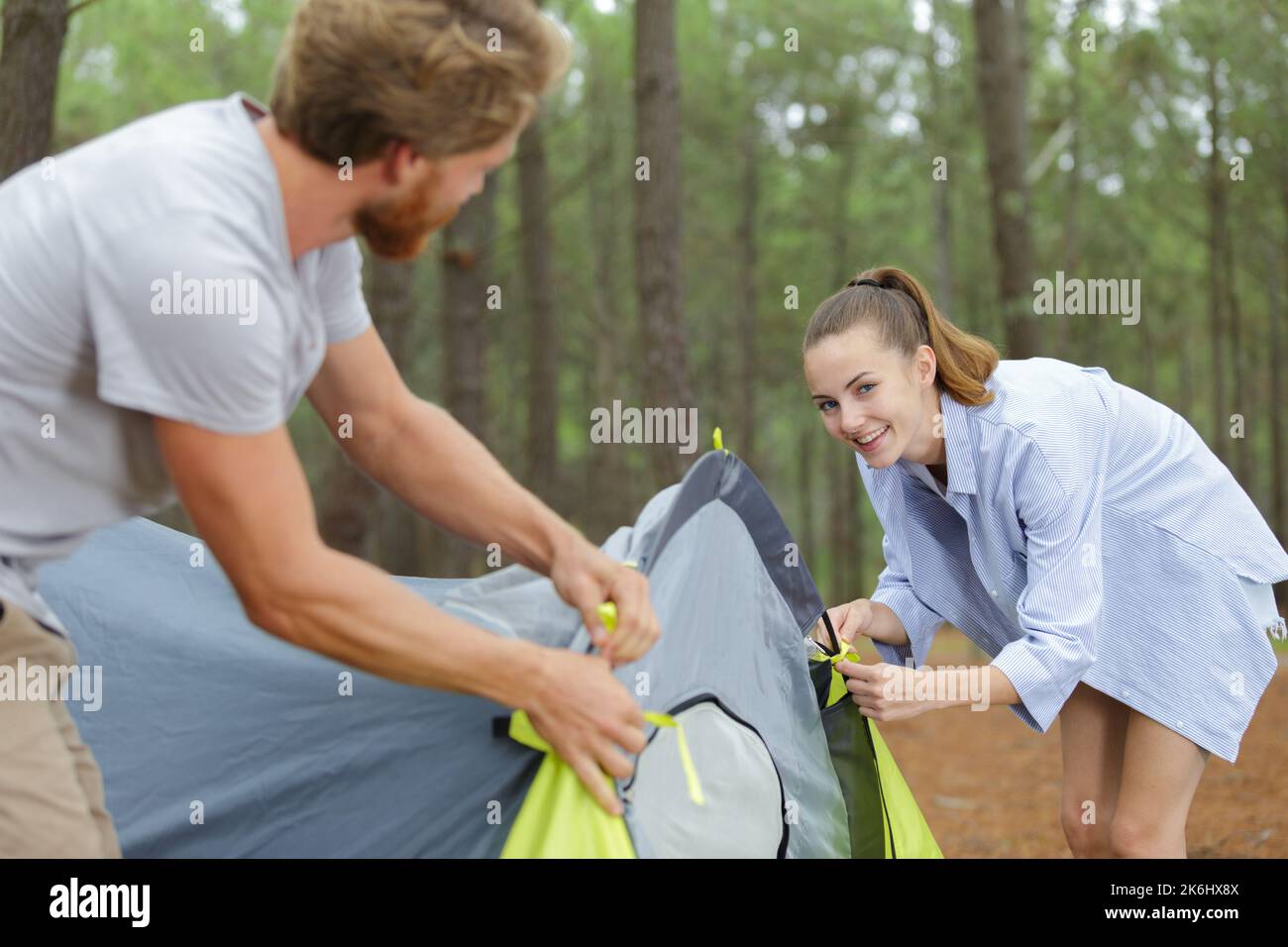 couple putting up a tent in the forest Stock Photo
