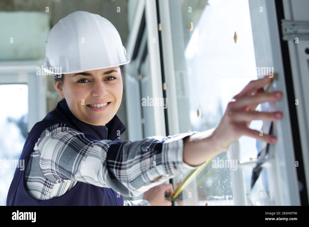 worker woman is checking dimensions of finished plastic window Stock Photo