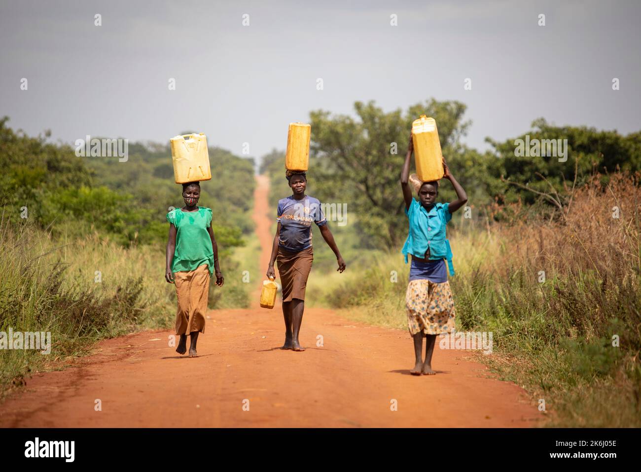 A girl and two women walk a long distance to bring water to their home in Abim District, Uganda, East Africa. Stock Photo