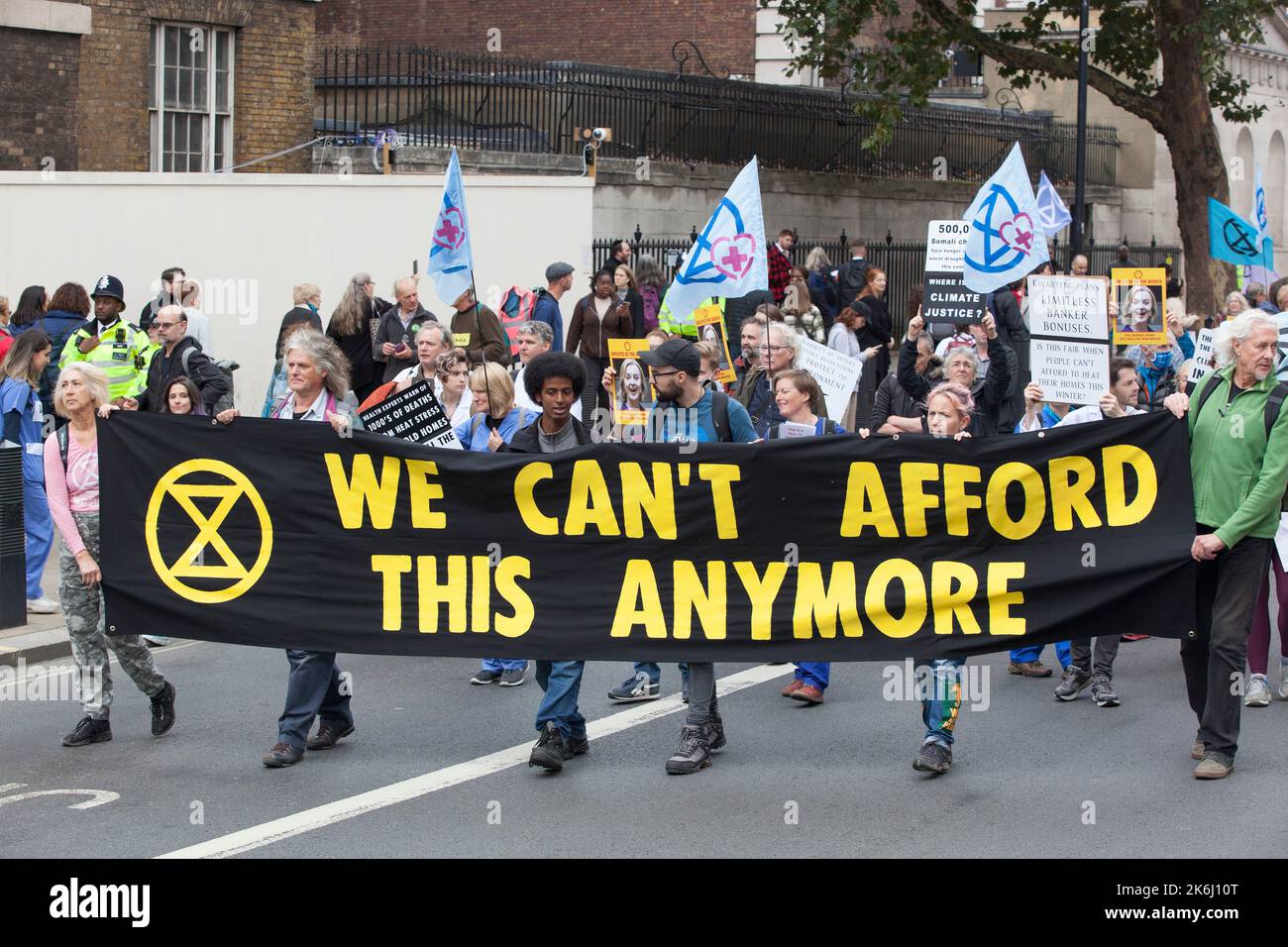 London, UK, 14 October 2022: Extinction Rebellion march down Whitehall to Downing Street, where they symbollically burned energy bills. The slogan of the protest was 'We Can't Afford This', referring both to energy bills in the cost of living crisis and to the climate crisis caused by burning fossil fuels. Posters showed Liz Truss as Employee of the Month, highlighting her connections to the fossil fuel industry. Anna Watson/Alamy Live News Stock Photo