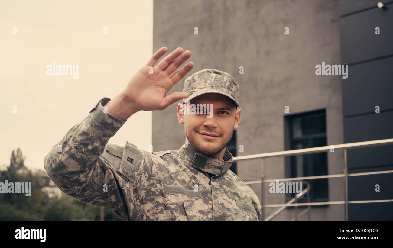 Smiling soldier in uniform and cap greeting while walking outdoors,stock image Stock Photo
