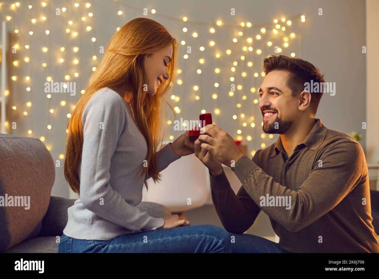 Happy young man proposing to his beloved woman and giving her gold engagement ring Stock Photo