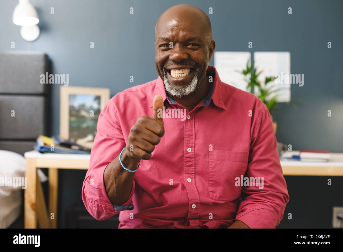 Happy african american senior man making video call smiling and giving thumb up sign to camera Stock Photo