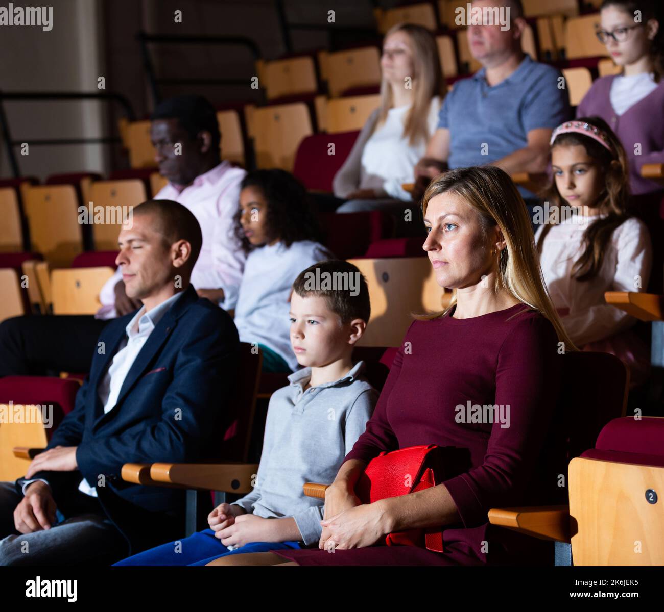 Family of theatergoers with preteen son watching performance in theater ...