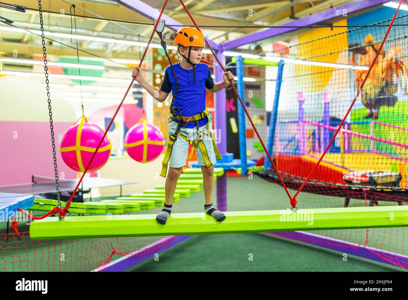 Boy in protective gear holding safety rope and passing obstacle course Stock Photo