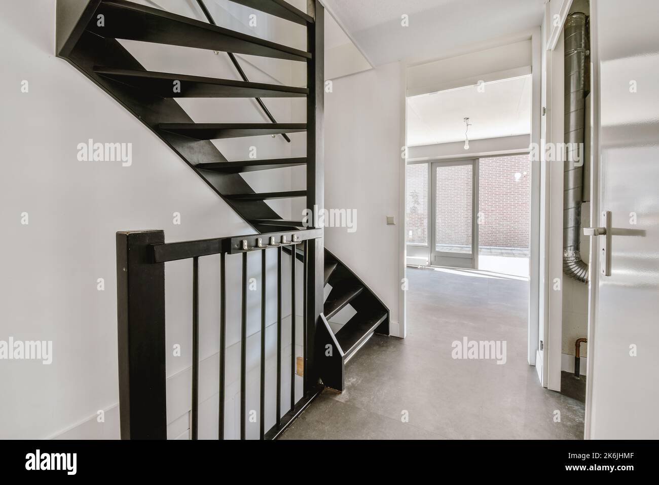 White hallway with wooden stairway leading to second floor of modern ...