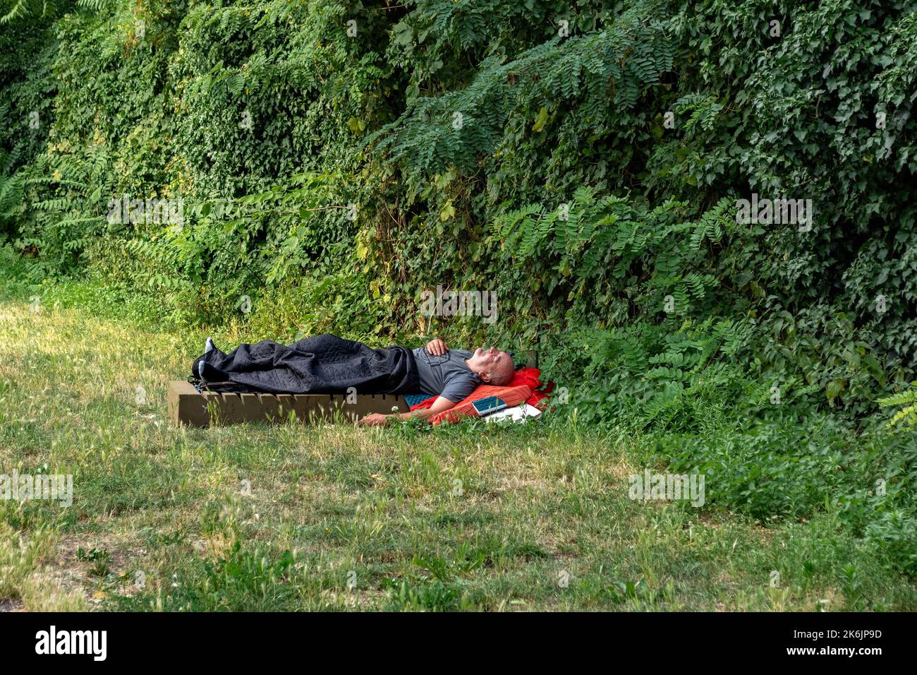 Berlin, Germany, July 21. A homeless man sleeps on a foam mattress in the open air in the city square, in the evening in Berlin on July 21, 2022. Stock Photo