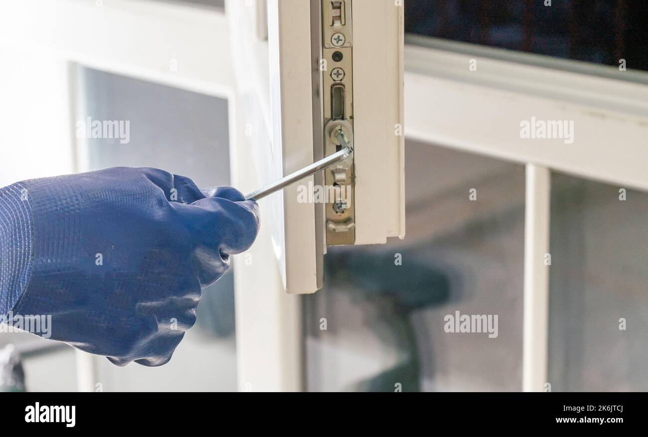 master with a screwdriver sets fittings on the window Stock Photo