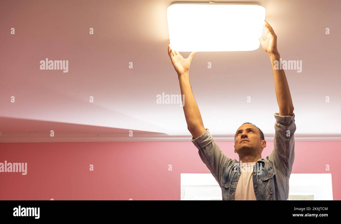 An electrician installs a chandelier on the ceiling. Hands of an