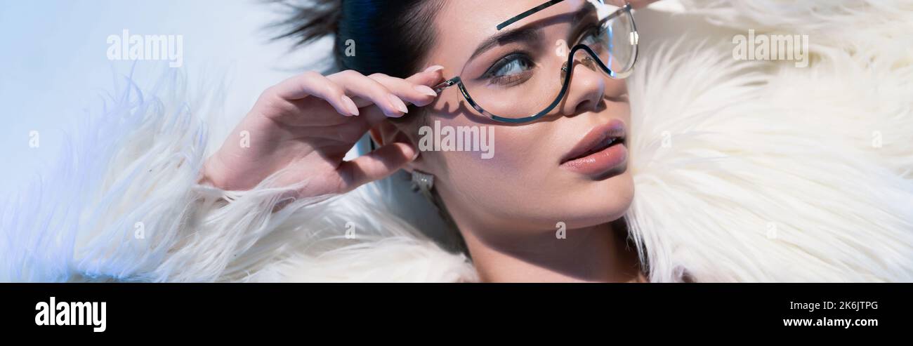 Top view of stylish woman in faux fur jacket touching sunglasses on ...