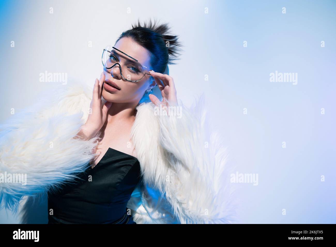 Top view of stylish woman in faux fur jacket and sunglasses looking at ...