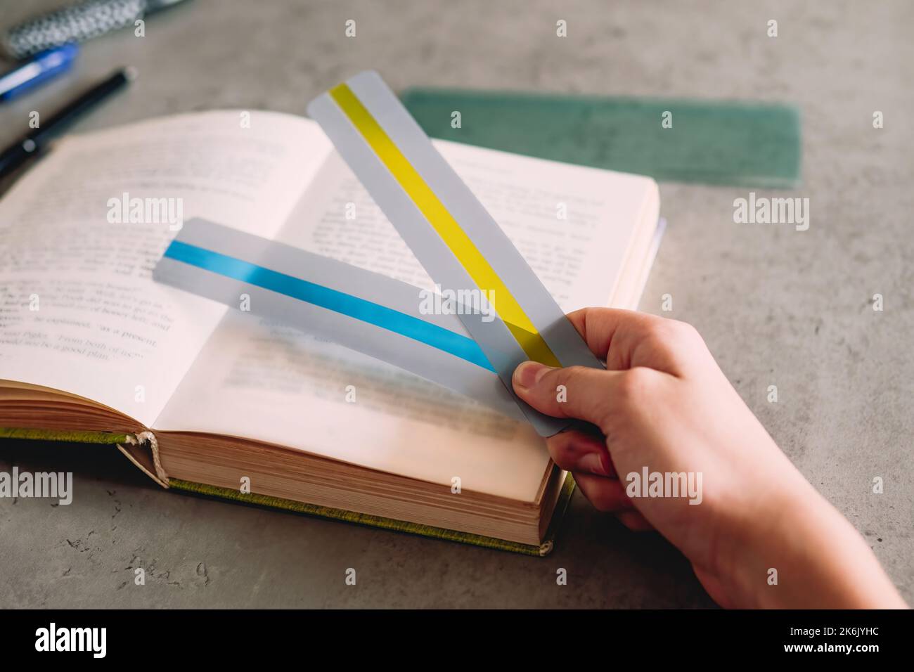 Reading tools for dyslexia. Child hand holding two colorful ruler overlay strips that help
