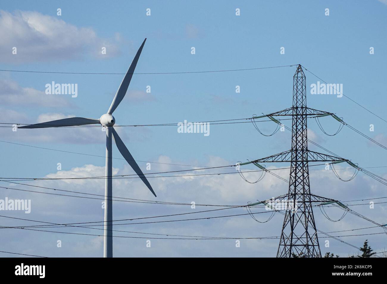 Wind turbine and electricity pylon on blue sky background Stock Photo