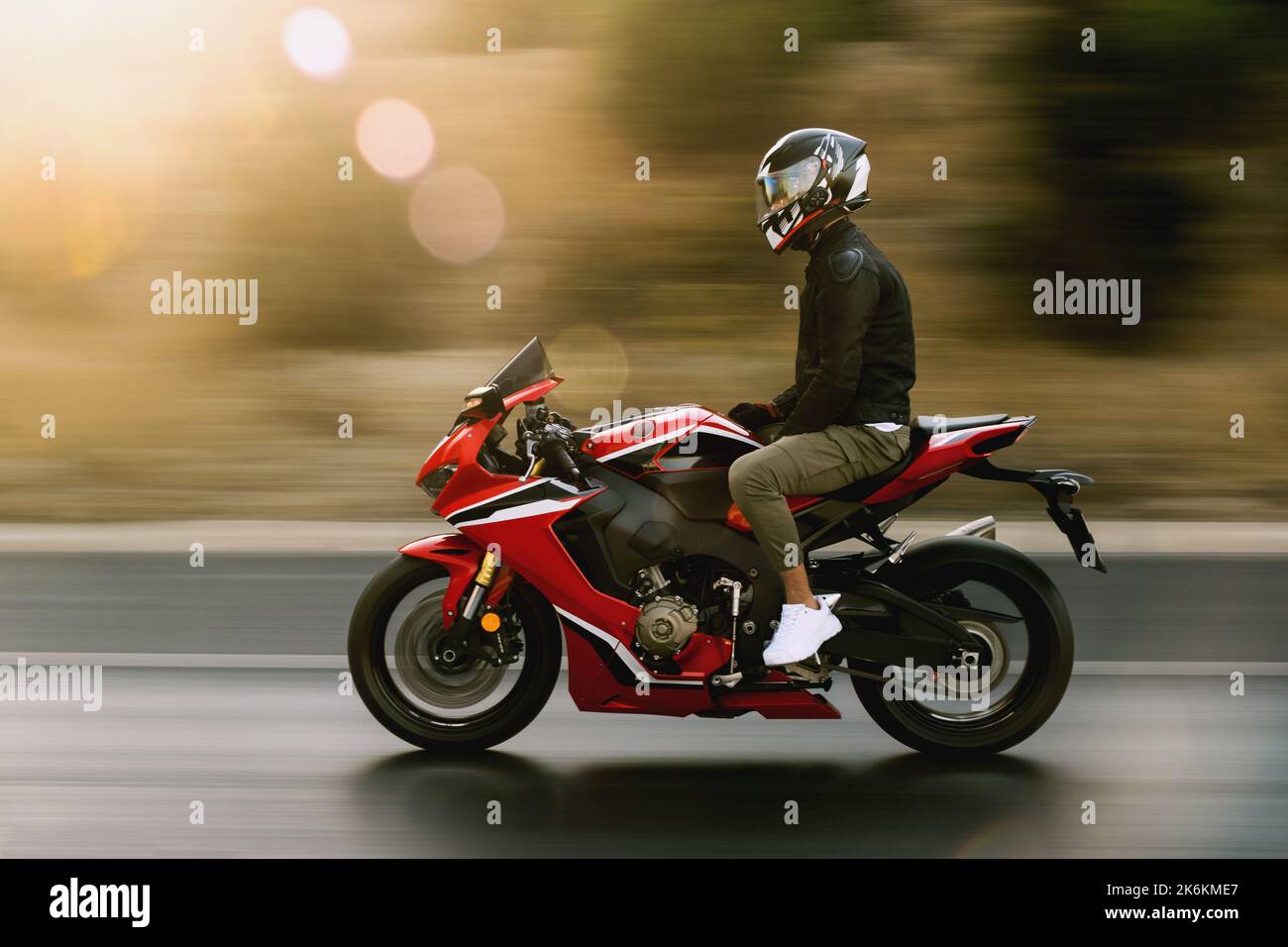 Man riding a red color racing motorcycle with no hands on highway. Stock Photo