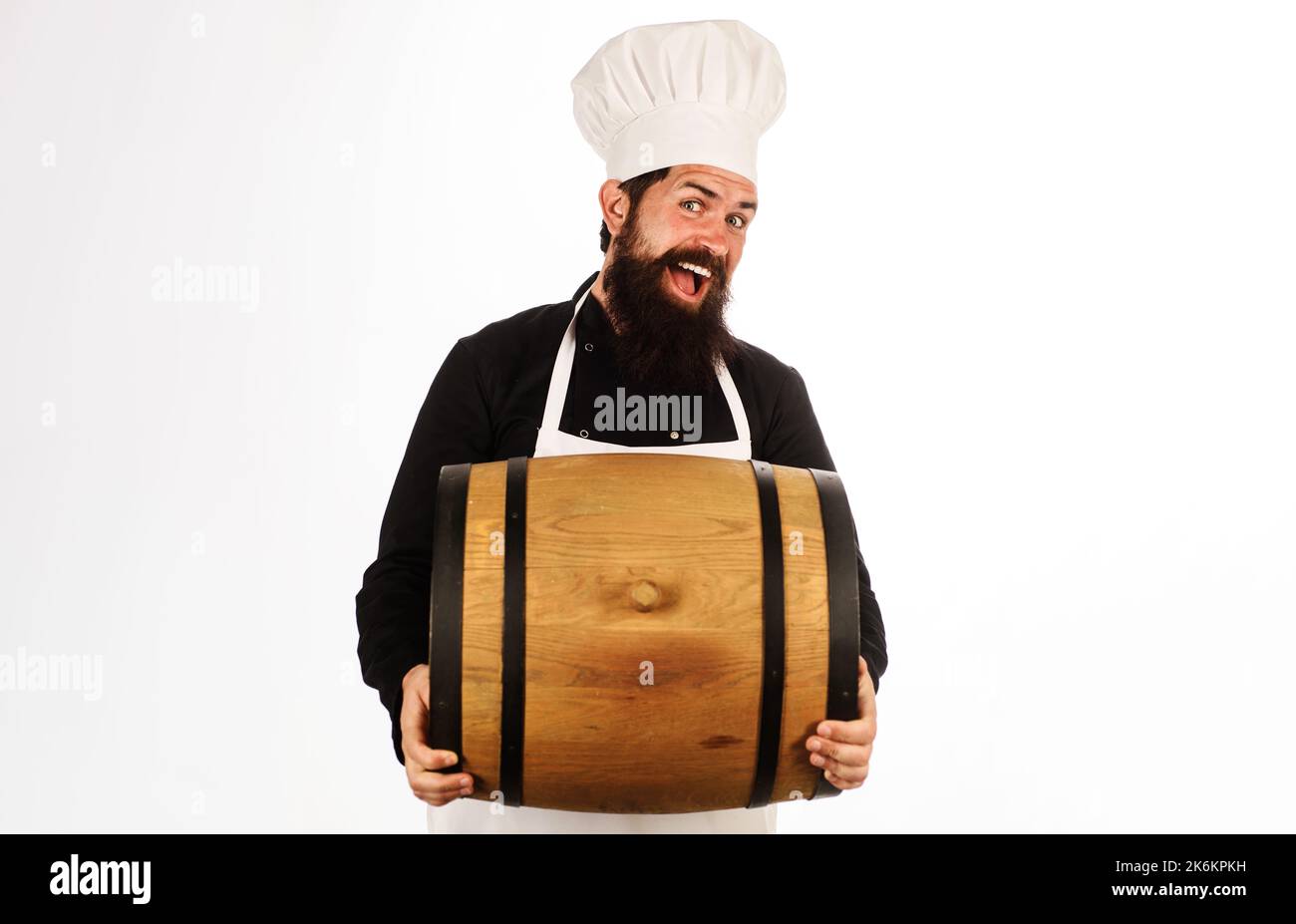 Brewer in brewery with wood barrel. Oktoberfest. Bearded man in chef hat and apron with cask wine. Stock Photo