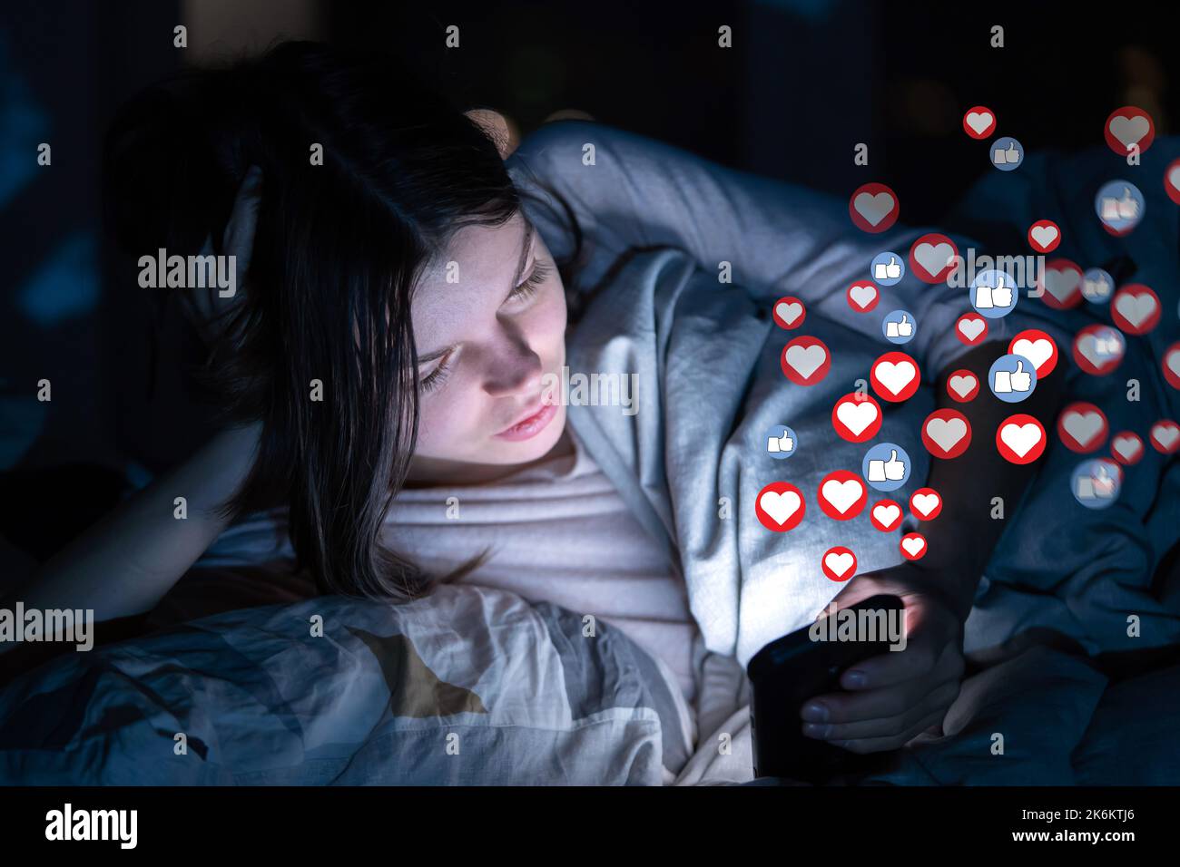 Girl with phone at night, receives hearts and likes. Stock Photo
