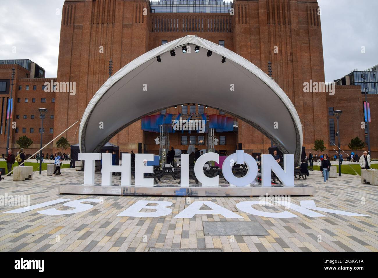 A sign states "The icon is back" next to a stage with performers