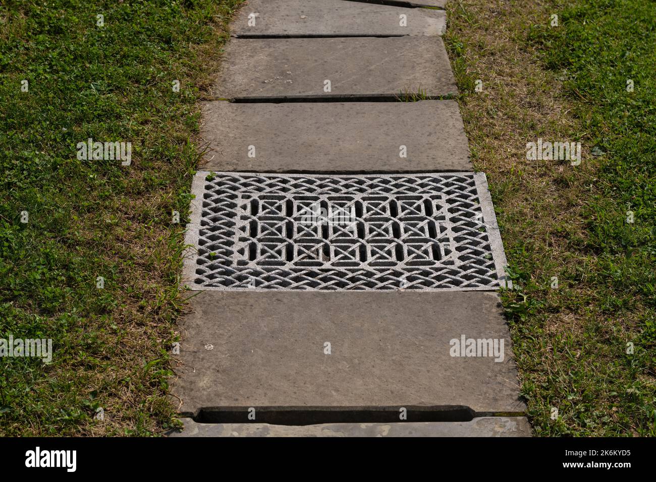 Iron gutter with grate cover of drainage system on pedestrian walkway