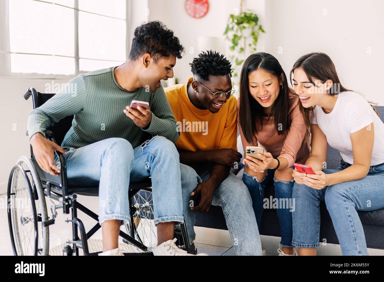 Group of diverse teenage people using smart mobile phone together at home Stock Photo