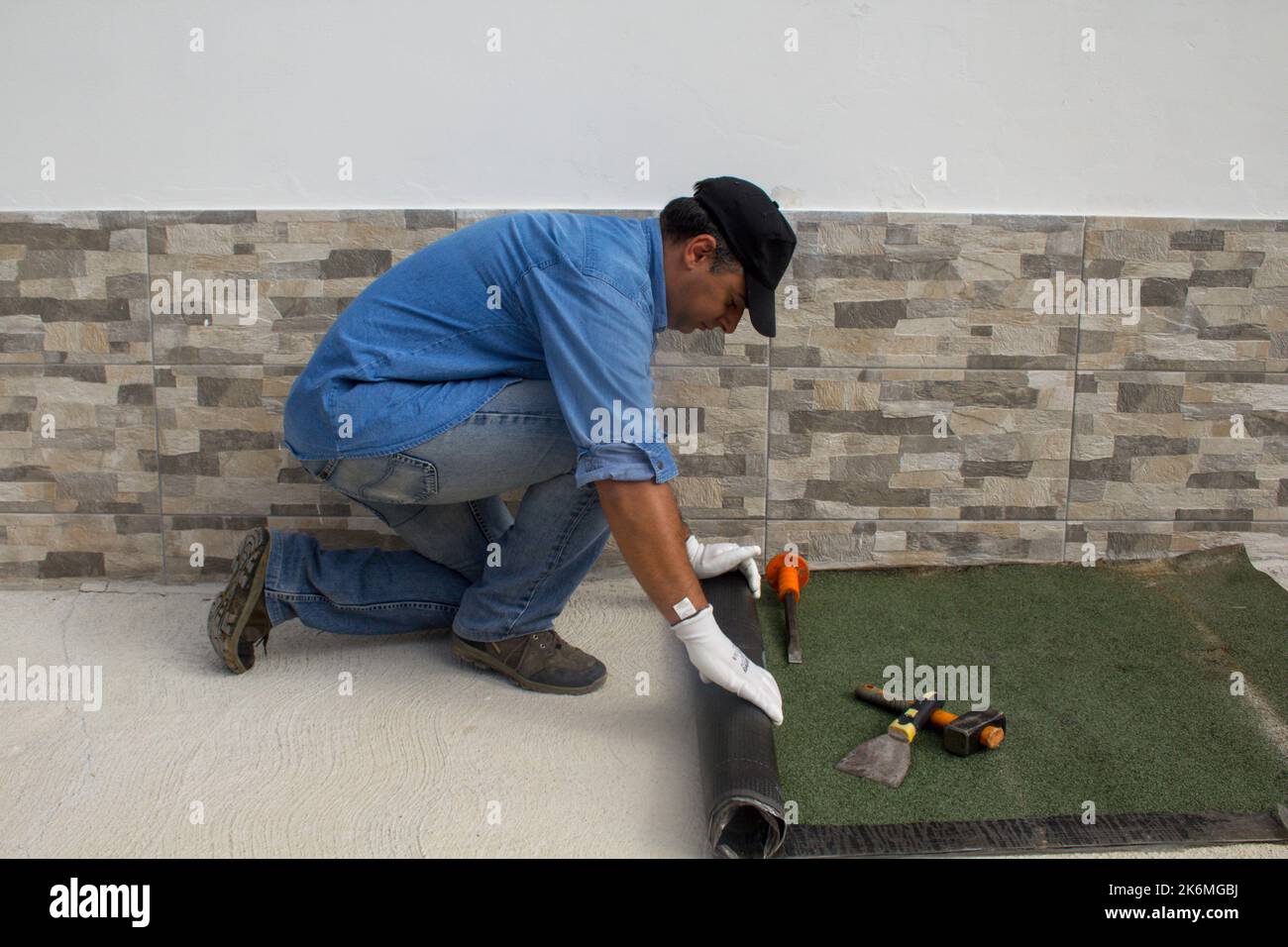 Construction worker at work while unrolling the tarred bituminous sheath to protect roofs and floors from bad weather and rain. Insulation in the hous Stock Photo