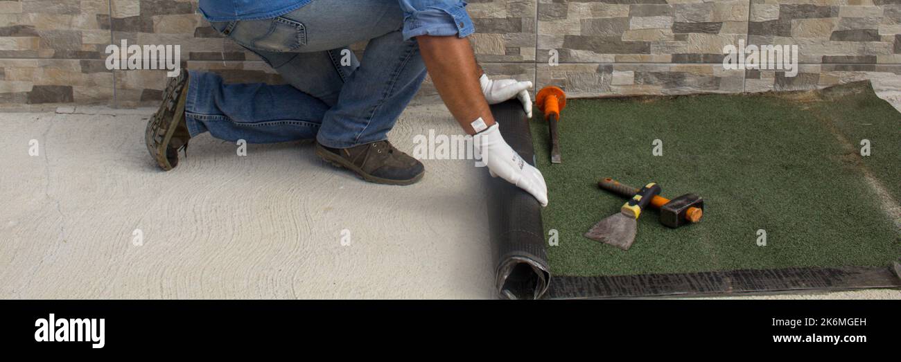 Construction worker at work while unrolling the tarred bituminous sheath to protect roofs and floors from bad weather and rain. Insulation in the hous Stock Photo