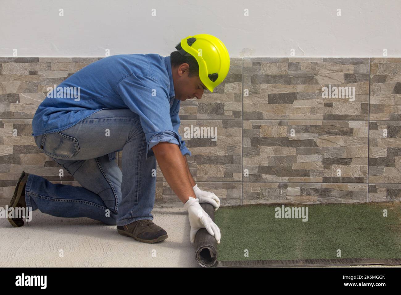 Construction worker at work while unrolling the tarred bituminous sheath to protect roofs and floors from bad weather and rain. Insulation house Stock Photo