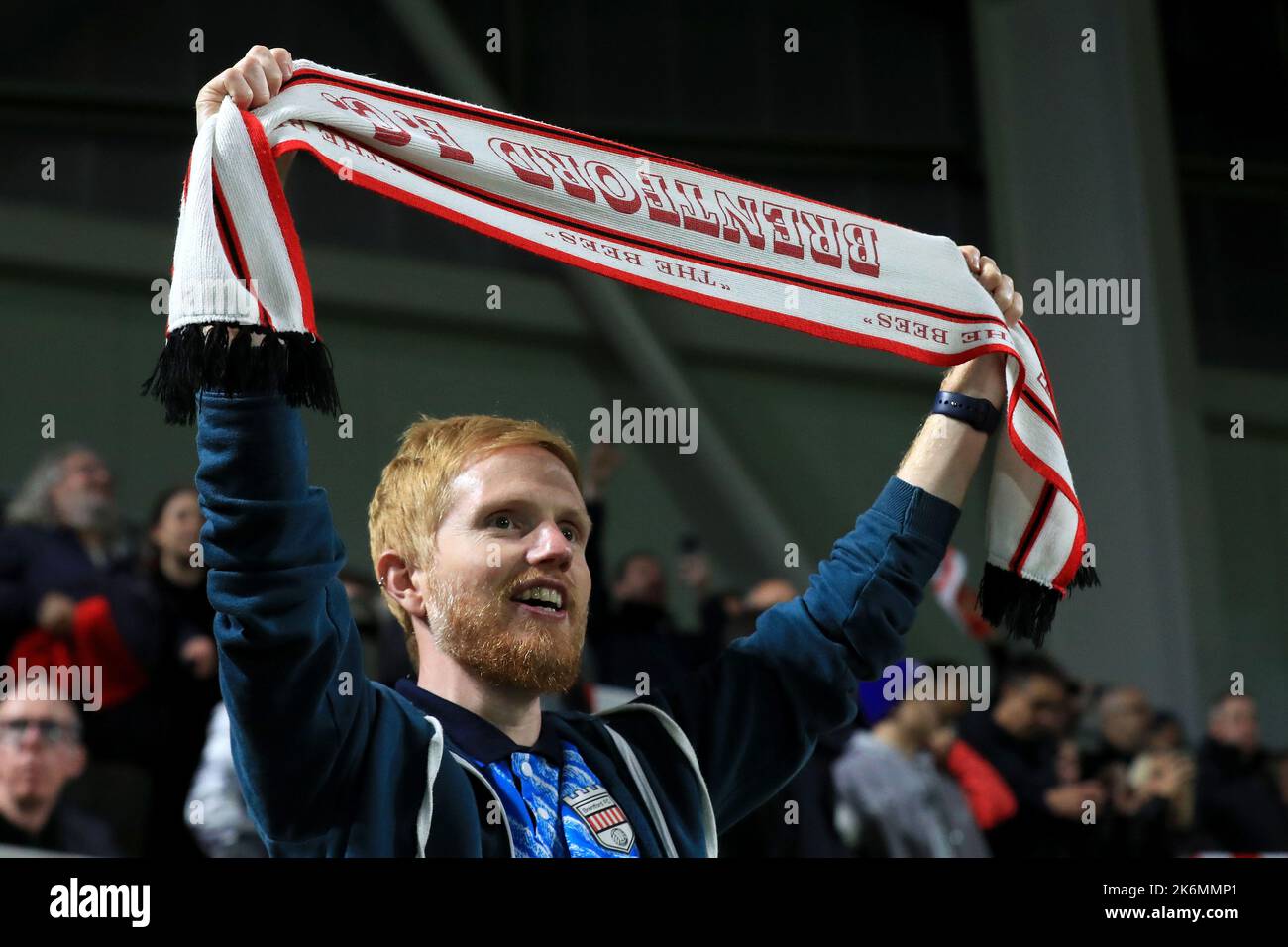 A Brentford fan holds his scarf aloft during ÒHey JudeÓ during the Premier League match Brentford vs Brighton and Hove Albion at Brentford Community Stadium, London, United Kingdom, 14th October 2022  (Photo by Carlton Myrie/News Images) Stock Photo