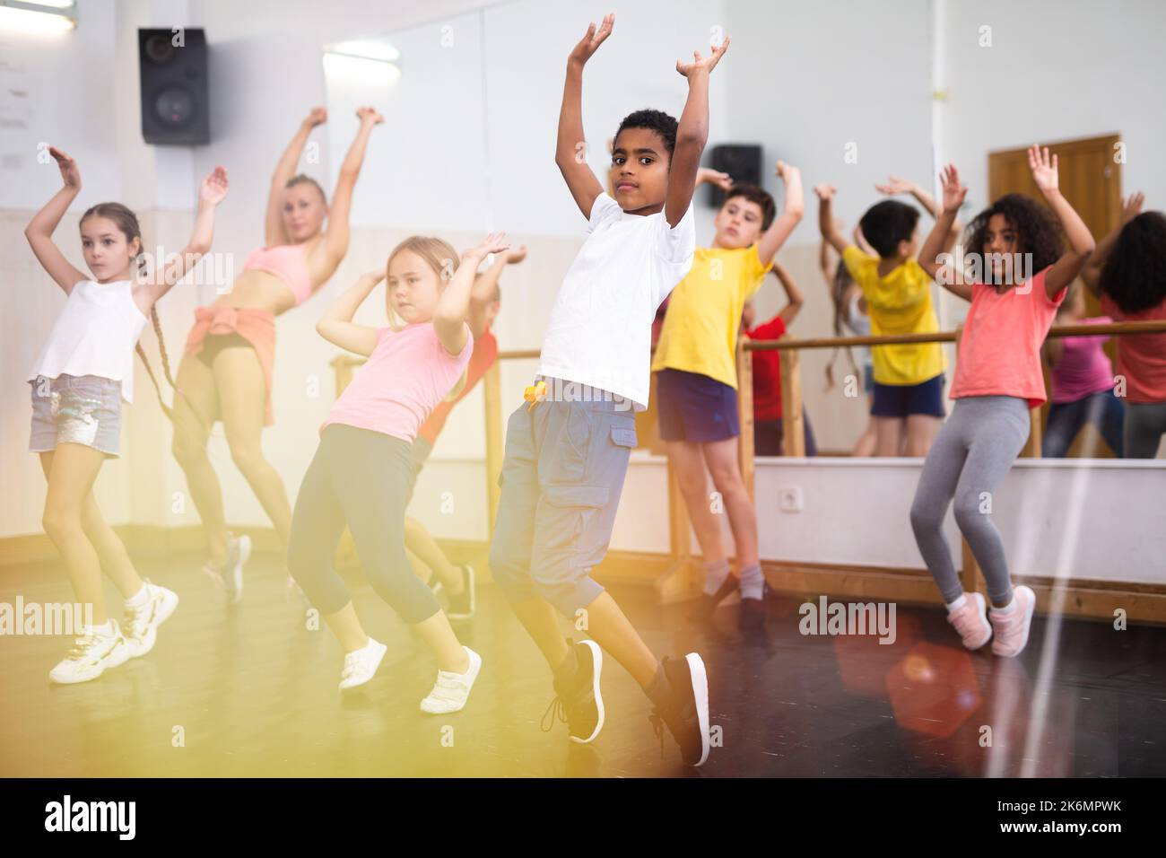 Preteen children practicing dance moves near ballet barre Stock Photo